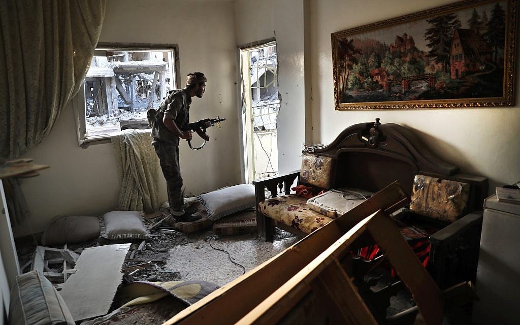 A US-backed Syrian Democratic Forces fighter, looks through a window as he takes his position inside a destroyed apartment on the front line, in Raqqa, northeast Syria, July 27, 2017. (AP Photo/Hussein Malla)
