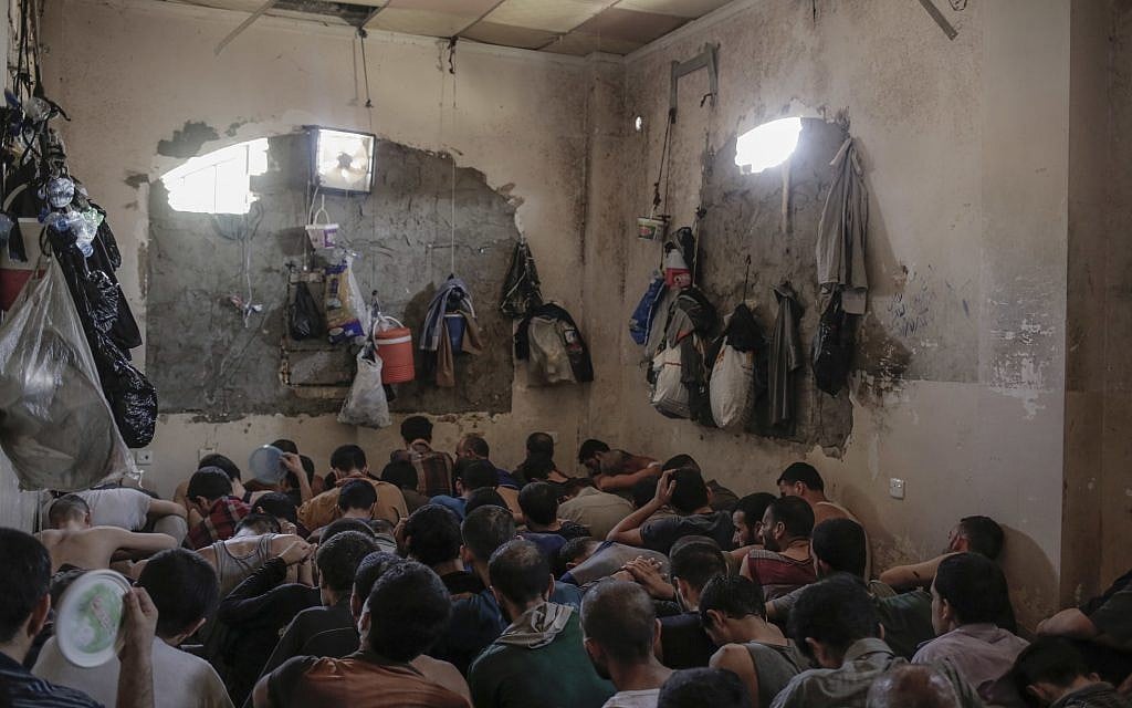 More than 100 Islamic State suspects sit inside a small room in a prison south of Mosul, July 18, 2017. A total of more 370 IS suspects are being held in bad conditions in the prison. (AP Photo/Bram Janssen)