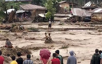 Villagers cross raging flood waters in Lanao del Norte, Zamboanga Pennisula, southern Philippines on Friday, December 22, 2017 (Aclimah Disumala via the AP)