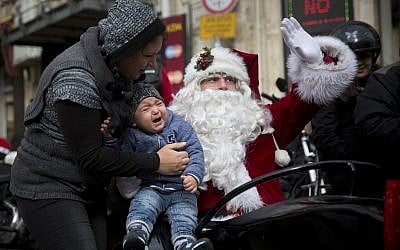 Illustrative: A man dressed as Santa Claus waves from a sidecar of a motorbike on Christmas Eve in Jerusalem Old City, Decemeber 24, 2017. (AP Photo/Oded Balilty)