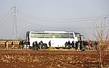 In this photo released on Friday, December 29, 2017 by the Syrian official news agency SANA, Syrian government forces stand next to a bus which is waiting to evacuate Syrian rebels and their families from Beit Jinn village, in the southern province of Daraa, Syria. (SANA via AP)