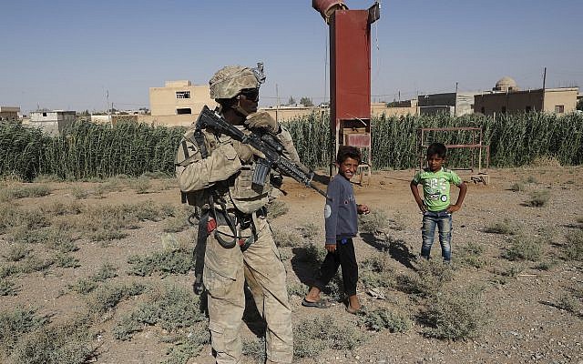 A US soldier stands near Syrian children on a road that links to Raqqa, Syria, Wednesday, July 26, 2017 (AP Photo/Hussein Malla) A US soldier stands near Syrian children on a road that links to Raqqa, Syria, Wednesday, July 26, 2017 (AP Photo/Hussein Malla)