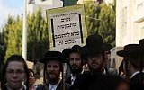 Ultra-Orthodox Jews stand in front of a sign in Beit Shemesh asking women not to loiter there on December 26, 2011. (Kobi Gideon/Flash90)