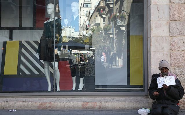 A man begs for money near a window display in the center of Jerusalem. October 22, 2013. (Nati Shohat/Flash90) A man begs for money near a window display in the center of Jerusalem. October 22, 2013. (Nati Shohat/Flash90)