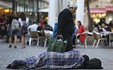 People walk by a homeless man sleeping on the street, near cafes in the center of Jerusalem. November 10, 2013. (Nati Shohat/FLASH90/File)