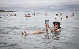 A woman reads a newspaper while floating in the Dead Sea, May 20, 2017. (Yossi Zamir/Flash90)
