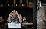 A man reads the newspaper at a cafe at the Mahane Yehuda Market in Jerusalem, on September 5, 2017. (Hadas Parush/Flash90)