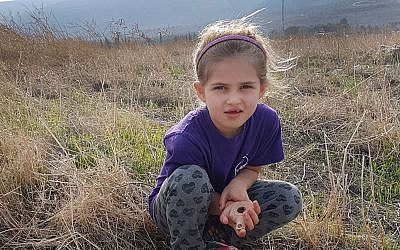Seven-year-old Hadas Goldberg-Keidar from Kibbutz Heftziba with the intact 2,200-year-old clay lamp next to porcupines' cave in the Beit She'an Valley. (Israel Antiquities Authority)