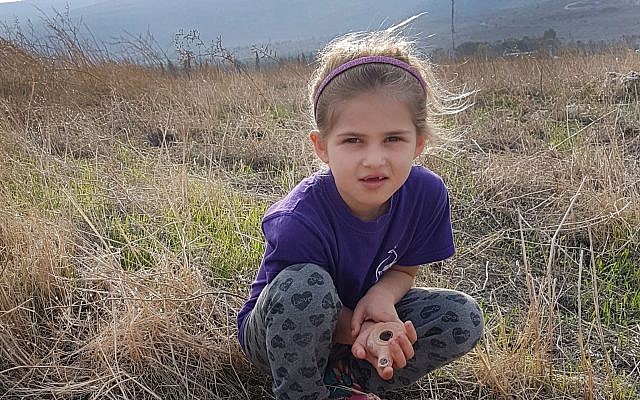 Seven-year-old Hadas Goldberg-Keidar from Kibbutz Heftziba with the intact 2,200-year-old clay lamp next to porcupines' cave in the Beit She'an Valley. (Israel Antiquities Authority)