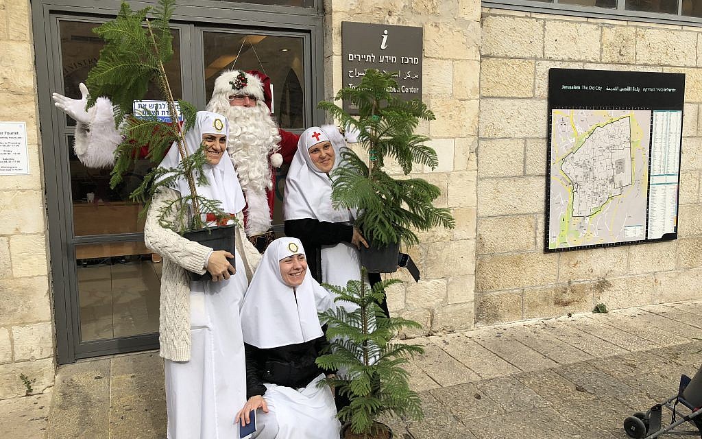 Jerusalem Santa, Issa Kassissieh, poses with locals coming to pick up free Christmas trees on Thursday, December 21 (Jessica Steinberg/Times of Israel)