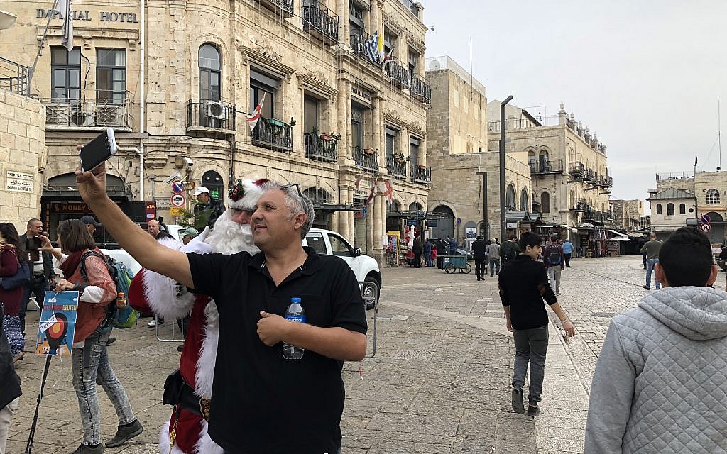 The Jerusalem Santa taking selfies outside Jaffa Gate on Thursday, December 21, 2017 (Jessica Steinberg/Times of Israel)