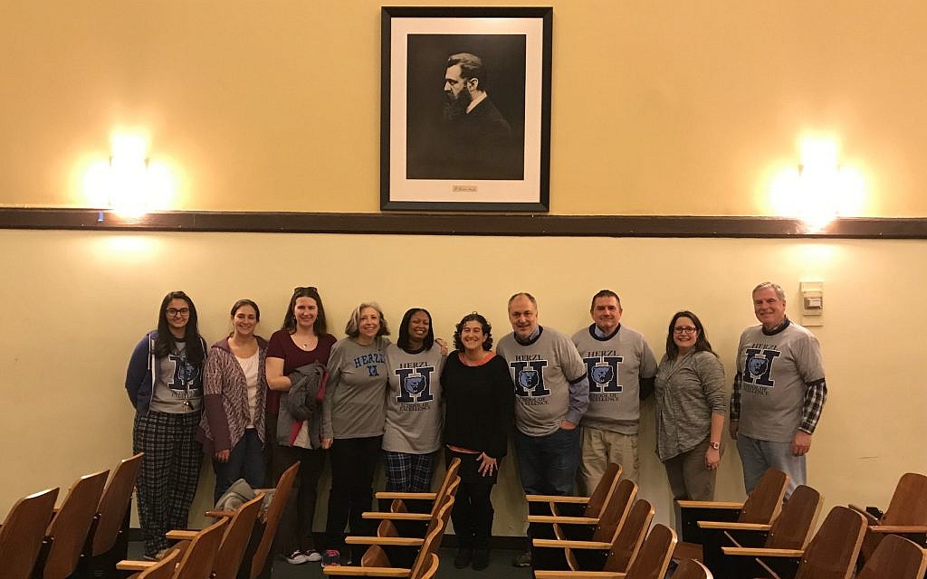 Temple Beth Israel's director of congregational learning Lori Sagarin (fourth from left), Theodore Herzl School principal Tamara Davis (fifth from left) and others beneath Theodor Herzl portrait donated to school by Herzl collector David Matlow, Chicago, December 18, 2017. (Courtesy) Temple Beth Israel's director of congregational learning Lori Sagarin (fourth from left), Theodore Herzl School principal Tamara Davis (fifth from left) and others beneath Theodor Herzl portrait donated to school by Herzl collector David Matlow, Chicago, December 18, 2017. (Courtesy)