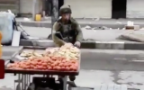 An Israeli soldier apparently steals fruit from a Palestinian vendor during a violent demonstration in the West Bank city of Hebron on December 10, 2017. (Screen capture)