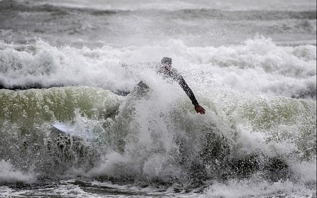 An man surfs in the Israeli coastal city of Netanya on January 5, 2018 as a storm hits the country. / AFP PHOTO / JACK GUEZ An man surfs in the Israeli coastal city of Netanya on January 5, 2018 as a storm hits the country. / AFP PHOTO / JACK GUEZ