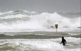 A surfer enters the Mediterranean Sea off the coastal city of Netanya on January 5, 2018, as the worst storm of the winter hits Israel. (AFP Photo/Jack Guez)