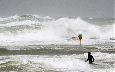 A surfer enters the Mediterranean Sea off the coastal city of Netanya on January 5, 2018, as the worst storm of the winter hits Israel. (AFP Photo/Jack Guez)
