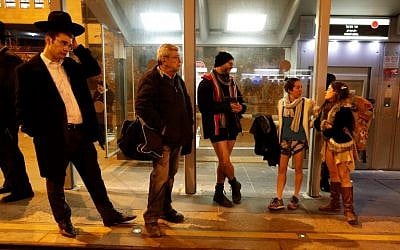 People taking part in the annual international "No Pants Subway Ride" day wait for the Jerusalem light train on January 7, 2018. (AFP PHOTO / AHMAD GHARABLI)
