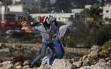 Illustrative. Palestinians protesters throw a firebomb towards Israeli security forces during clashes, on January 12, 2018, north of Ramallah in the West Bank. (AFP/Abbas Momani)