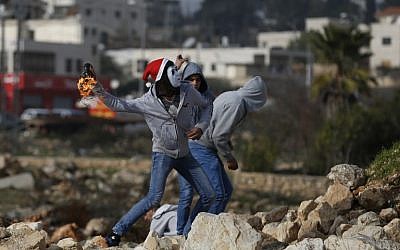 Illustrative. Palestinians protesters throw a firebomb towards Israeli security forces during clashes, on January 12, 2018, north of Ramallah in the West Bank. (AFP/Abbas Momani)