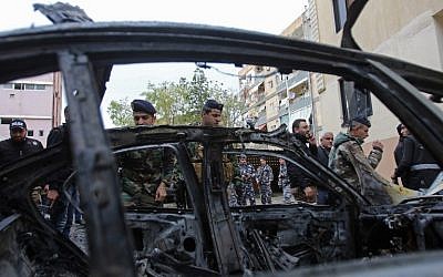 Lebanese security forces check a damaged vehicle following a car bomb blast in the southern Lebanese port city of Sidon on January 14, 2018.  / AFP PHOTO / Mahmoud ZAYYAT
