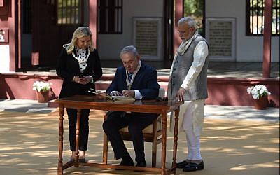 Prime Minister Benjamin Netanyahu (C) signs a visitors book as his wife Sara Netanyahu (L) and Indian Prime Minister Narendra Modi look on during a visit to the Gandhi Ashram in Ahmedabad on January 17, 2018. (AFP Photo/Sam Panthaky)