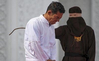Jono Simbolon (front), an Indonesian Christian, grimaces in pain as he is flogged in front of a crowd outside a mosque in Banda Aceh, Aceh province, on January 19, 2018. (AFP PHOTO / CHAIDEER MAHYUDDIN)