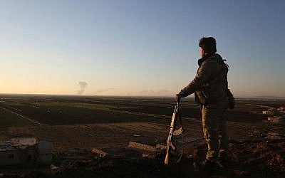 A Syrian rebel fighter stands in the Tal Malid area, north of Aleppo, as he watches smoke billow from a Kurdish People's Protection Units (YPG) position in the area of Afrin, on January 20, 2018. (AFP Photo/Nazeer al-Khatib)