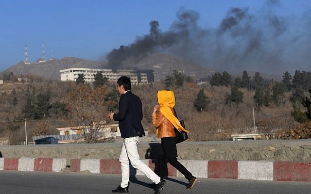 Afghans walk near the Intercontinental Hotel as smoke billows during a fight between gunmen and Afghan security forces in Kabul on January 21, 2018. (AFP PHOTO/WAKIL KOHSAR) Afghans walk near the Intercontinental Hotel as smoke billows during a fight between gunmen and Afghan security forces in Kabul on January 21, 2018. (AFP PHOTO/WAKIL KOHSAR)