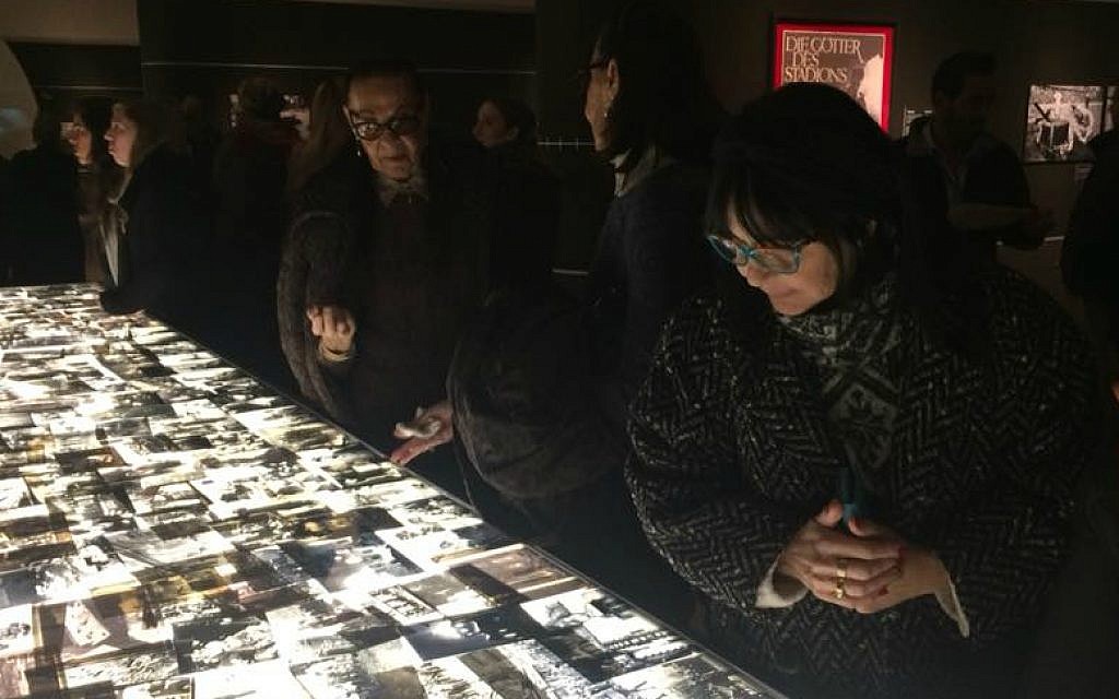 Visitors looks at hundreds of Holocaust-era images displayed on light table at opening of 'Flashes of Memory' exhibition at Yad Vashem, January 24, 2018 (Renee Ghert-Zand/TOI)