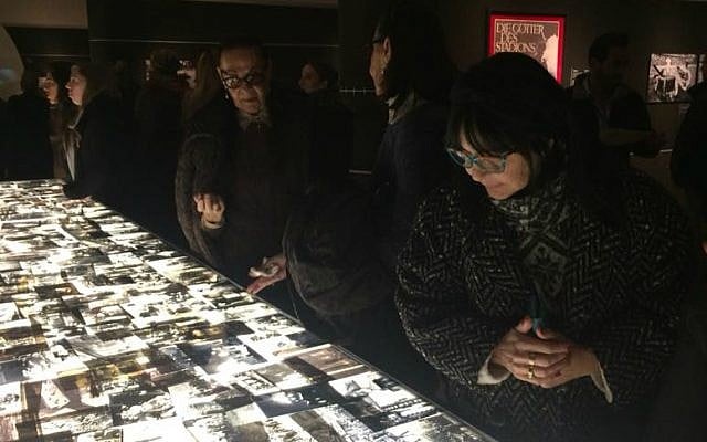 Visitors looks at hundreds of Holocaust-era images displayed on light table at opening of 'Flashes of Memory' exhibition at Yad Vashem, January 24, 2018 (Renee Ghert-Zand/TOI)