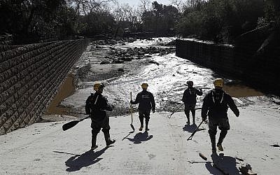 Members of the Los Angeles County Fire Department Search and Rescue crew walk toward flooded waters in Montecito, California, on Wednesday, January 10, 2018. (AP/Marcio Jose Sanchez)