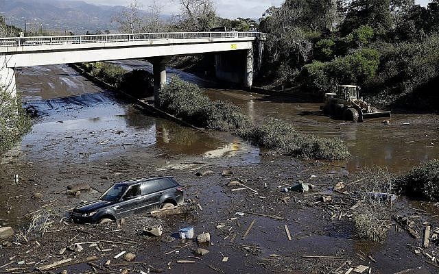 A bulldozer moves debris as a vehicle sits stranded in flooded water on U.S. Highway 101 in Montecito, Calif., Wednesday, Jan. 10, 2018. Dozens of homes were swept away or heavily damaged and several people were killed Tuesday as downpours sent mud and boulders roaring down hills stripped of vegetation by a gigantic wildfire that raged in Southern California last month. (AP Photo/Marcio Jose Sanchez)