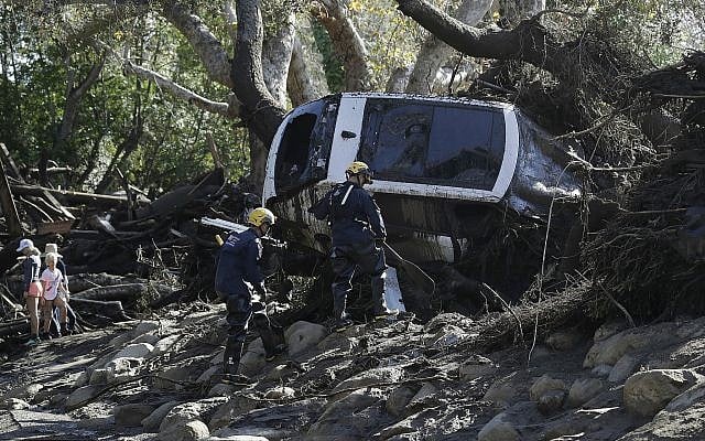 Members of the Los Angeles County Fire Department Search and Rescue crew work on a car trapped under debris in Montecito, Calif., Wednesday, Jan. 10, 2018. Dozens of homes were swept away or heavily damaged and several people were killed Tuesday as downpours sent mud and boulders roaring down hills stripped of vegetation by a gigantic wildfire that raged in Southern California last month. (AP Photo/Marcio Jose Sanchez)