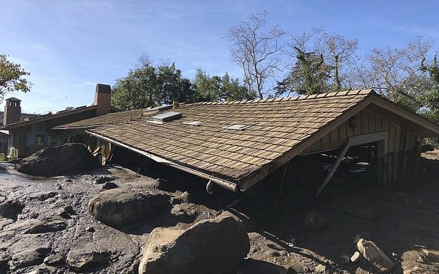 In this photo provided by Santa Barbara County Fire Department, mudflow, boulders, and debris from heavy rain runoff from early Tuesday reached the roof of a single story home in Montecito, Calif., on Wednesday, Jan. 10, 2018. A storm caused deadly mudslides in fire-scarred areas of Montecito and adjacent Santa Barbara County. (Mike Eliason/Santa Barbara County Fire Department via AP)