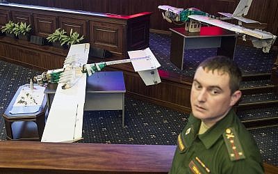 A Russian officer stands next to drones that attacked the Russian air base in Syria and were captured by the Russian military are displayed at a briefing in the Russian Defense Ministry in Moscow, Russia, Thursday, Jan. 11, 2018. (AP Photo/Pavel Golovkin)