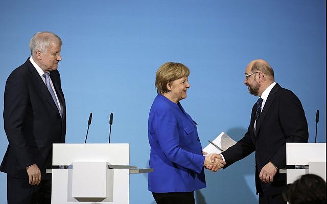 German Chancellor Angela Merkel, center, shakes hand with Social Democratic Party Chairman Martin Schulz as Bavarian governor Horst Seehofer, left, looks on during a joint statement after the exploratory talks between Merkel's Christian Democratic block and the Social Democrats on forming a new German government in Berlin, Germany, on January 12, 2018. (AP Photo/Markus Schreiber) German Chancellor Angela Merkel, center, shakes hand with Social Democratic Party Chairman Martin Schulz as Bavarian governor Horst Seehofer, left, looks on during a joint statement after the exploratory talks between Merkel's Christian Democratic block and the Social Democrats on forming a new German government in Berlin, Germany, on January 12, 2018. (AP Photo/Markus Schreiber)