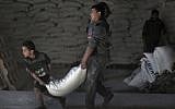 In this Jan. 14, 2018 photo, Palestinians receive food aid at a UNRWA warehouse in the Shati refugee camp, Gaza City. (AP Photo/Khalil Hamra)