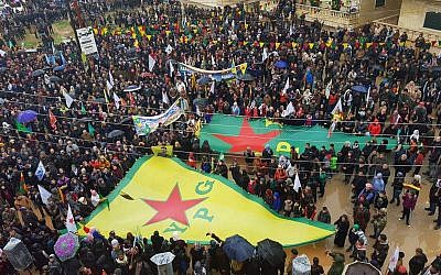 This photo released by the press office of the Kurdish People's Protection Units, or YPG, shows protesters waving giant flags of the YPG and other parties and militias, during a demonstration against Turkish threats, in Afrin, Aleppo province, Syria, on January 18, 2018. (YPG Press Office via AP)