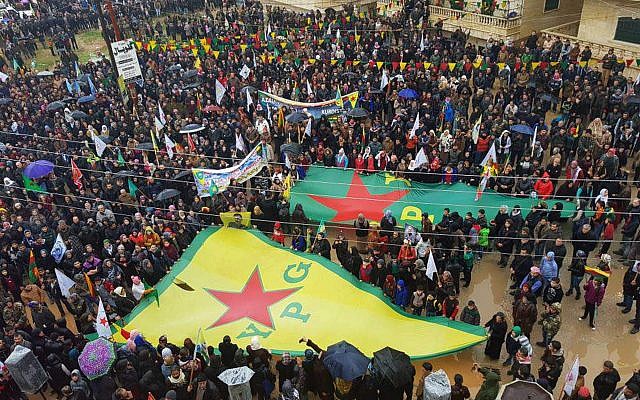 This photo released by the press office of the Kurdish People's Protection Units, or YPG, shows protesters waving giant flags of the YPG and other parties and militias, during a demonstration against Turkish threats, in Afrin, Aleppo province, Syria, on January 18, 2018. (YPG Press Office via AP) This photo released by the press office of the Kurdish People's Protection Units, or YPG, shows protesters waving giant flags of the YPG and other parties and militias, during a demonstration against Turkish threats, in Afrin, Aleppo province, Syria, on January 18, 2018. (YPG Press Office via AP)