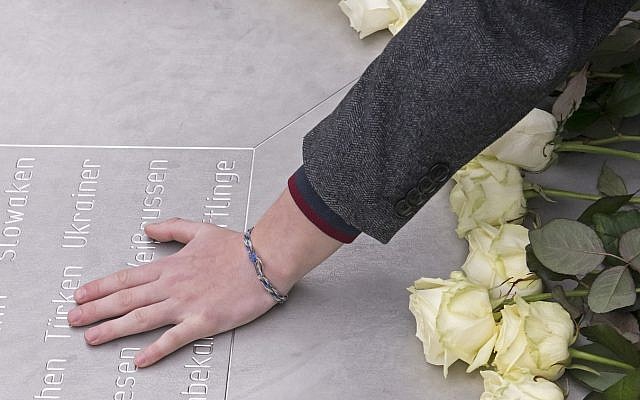 A woman holds her hand on a plain metal plaque during a wreath-layin  ceremony on occasion of the International Holocaust Remembrance Day in the former Nazi concentration camp Buchenwald near Weimar, Germany, Friday, Jan. 26, 2018. (AP Photo/Jens Meyer)