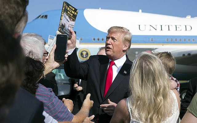 Illustrative image of US President Donald Trump holding up the book 'How Trump Won The Inside Story of a Revolution' on the tarmac at Palm Beach International Airport, December 22, 2017. (AP Photo/Carolyn Kaster) Illustrative image of US President Donald Trump holding up the book 'How Trump Won The Inside Story of a Revolution' on the tarmac at Palm Beach International Airport, December 22, 2017. (AP Photo/Carolyn Kaster)