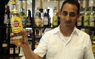 Illustrative: Wilbert Wilson Rivero, a Jewish bartender who works at Havana’s Hotel Raquel, proudly displays a bottle of Havana Club rum. (Larry Luxner/Times of Israel)
