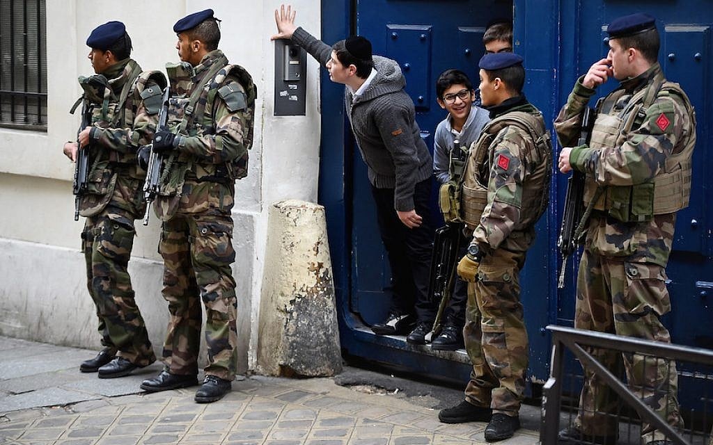 Illustrative: Children look out from a doorway as armed soldiers patrol outside a school in the Jewish quarter of the Marais district in Paris, January 13, 2015. (Jeff J. Mitchell/Getty Images/via JTA) Illustrative: Children look out from a doorway as armed soldiers patrol outside a school in the Jewish quarter of the Marais district in Paris, January 13, 2015. (Jeff J. Mitchell/Getty Images/via JTA)