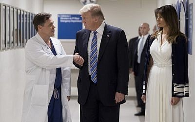 US President Donald Trump shakes hands with doctor Igor Nichiphorenko (L) beside First Lady Melania Trump while visiting first responders at Broward Health North hospital Pompano Beach, Florida, on February 16, 2018. (AFP PHOTO / JIM WATSON)