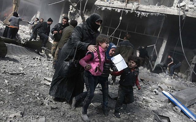 A Syrian woman and children run for cover amid the rubble of buildings following government bombing in the rebel-held town of Hamouria, in the besieged Eastern Ghouta region on the outskirts of the capital Damascus, on February 19, 2018.
(AFP/Abdulmonam Eassa)