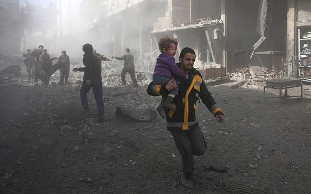 A Syrian man carries a child injured in government bombing in the rebel-held town of Hamouria, in the besieged Eastern Ghouta region on the outskirts of the capital Damascus, on February 19, 2018. (AFP PHOTO / ABDULMONAM EASSA)