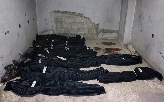 The bodies of Syrian civilians, including a baby (R), lie wrapped in shrouds on the floor of a makeshift clinic following Syrian government bombardments in Douma, in the besieged Eastern Ghouta region on the outskirts of the capital Damascus on February 22, 2018. (AFP PHOTO / Hamza AL-AJWEH)