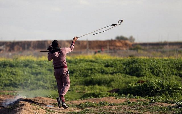 A Palestinian throws a rock toward Israeli soldiers during clashes near the border fence east of Gaza City on February 23, 2018. (AFP Photo/Mohammed Abed) A Palestinian throws a rock toward Israeli soldiers during clashes near the border fence east of Gaza City on February 23, 2018. (AFP Photo/Mohammed Abed)