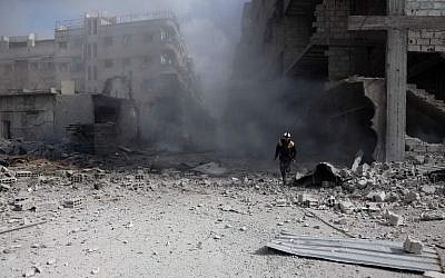 A Civil Defense volunteer, known as the White Helmets, checks the site of a regime air strike in the rebel-held town of Saqba, in the besieged Eastern Ghouta region on the outskirts of the capital Damascus, on February 23, 2018. (AFP Photo/Abdulmonam Essa)