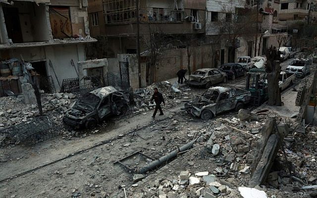 A picture taken on February 25, 2018, shows a Syrian man walking next to damaged buildings following regime air strikes in the Syrian rebel-held town of Douma, in the besieged Eastern Ghouta region on the outskirts of the capital Damascus. (AFP PHOTO / HAMZA AL-AJWEH)
